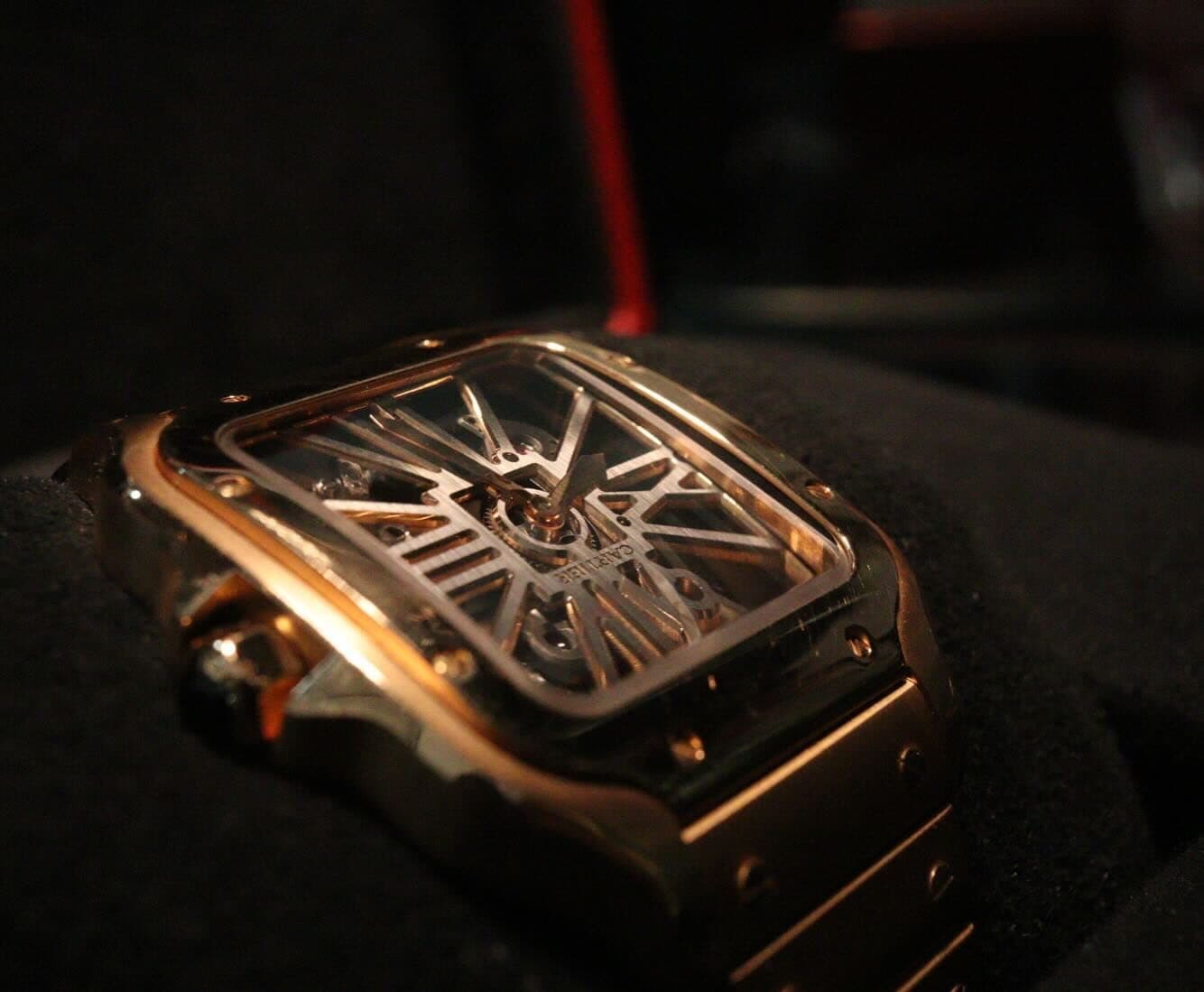 A skeleton watch on a black cushion, lit from one side.