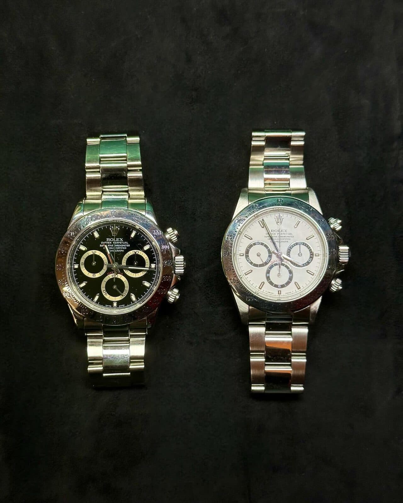 Two chronographs side by side on black cloth.
